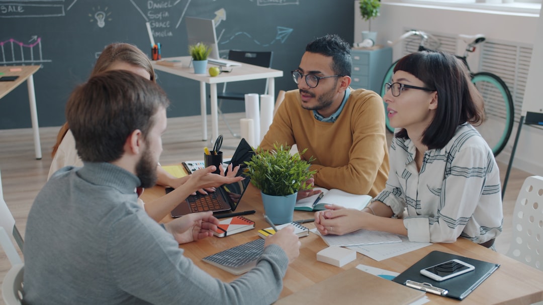 Multi-ethnic group of people are doing high-five talking and laughing in creative shared office during staff meeting. Communi