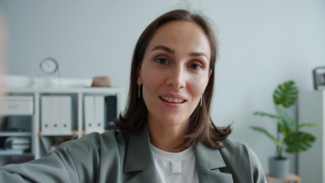 Portrait of pretty businesswoman making video call from office talking waving hand enjoying friendly conversation smilin